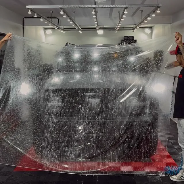 SUV preto dentro do estúdio, com a película recém-colocada na frente ainda cheia de solução de aplicação